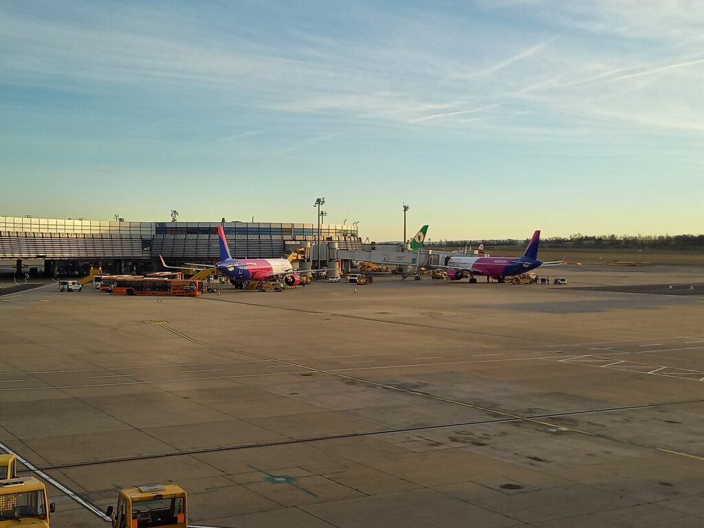 Dvě letadla Wizz Air stojí u nástupních mostů na odbavovací ploše letiště